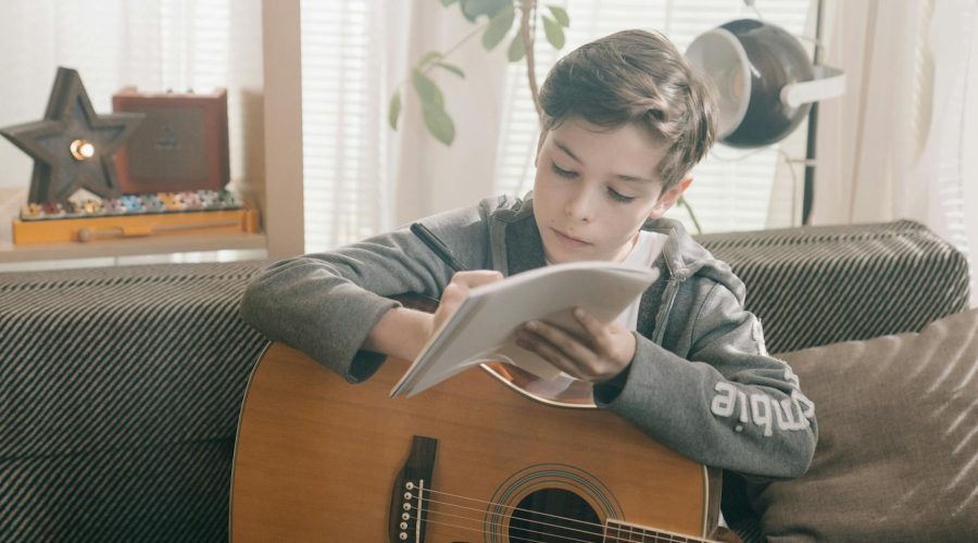 man in gray jacket playing acoustic guitar